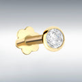 Gold labret stud with a clear gemstone on a gray background