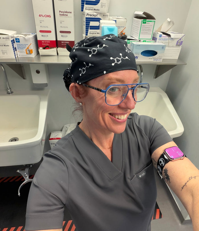 Ladyspinedoc wearing a scrub hat with molecular designs in a medical setting.