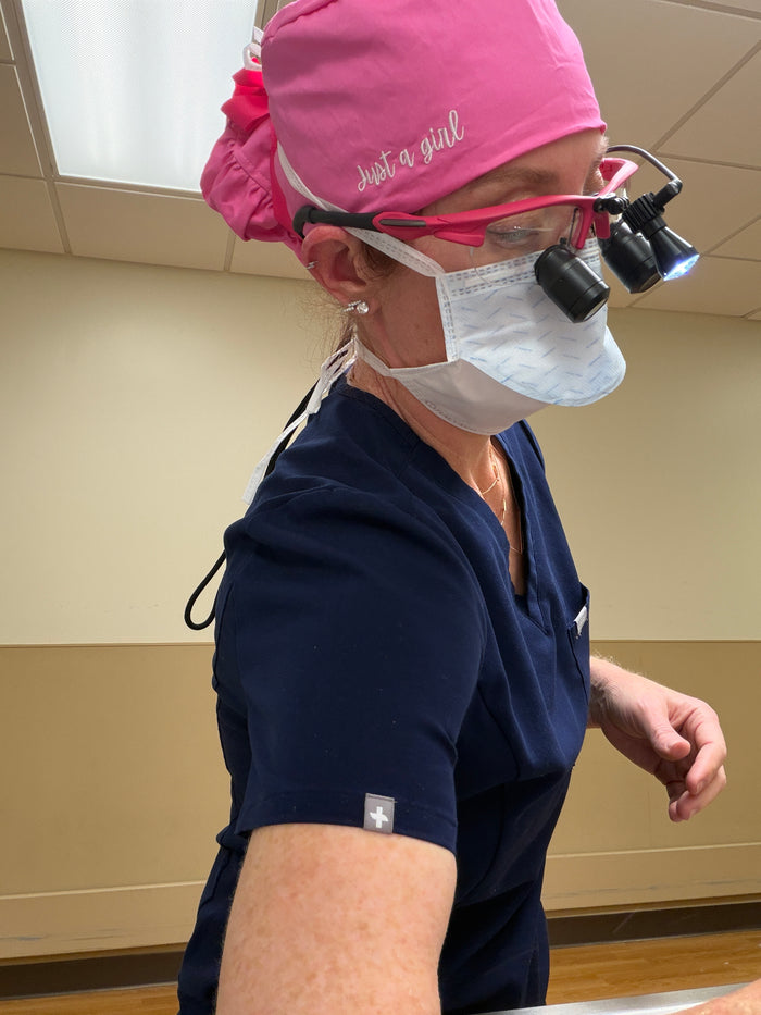 Ladyspinedoc wearing surgical attire with a Dr. Daisy "Just a girl" pink scrub cap and mask in a medical setting