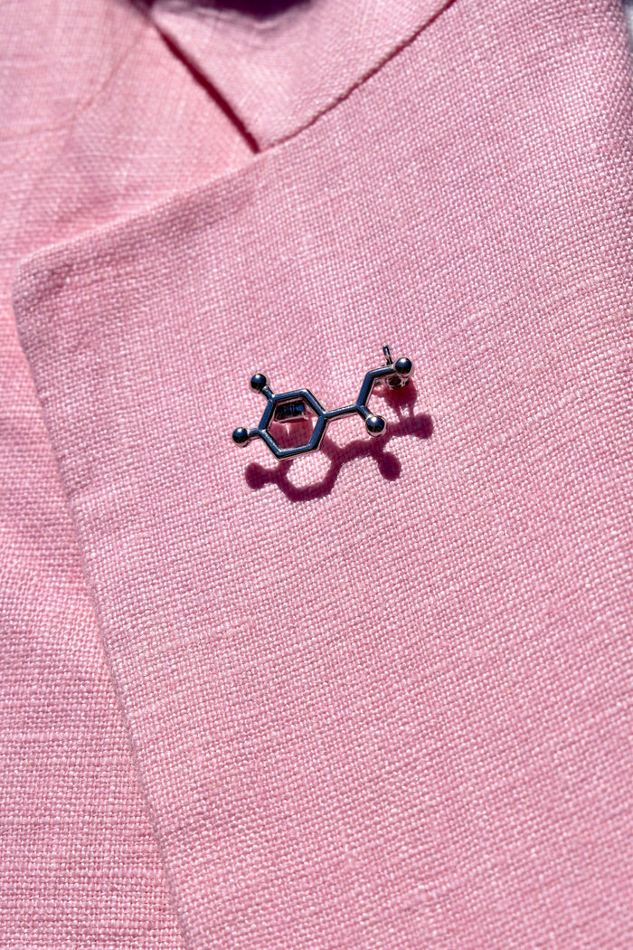 Close up of Noradrenaline Molecule Lapel Pin on pink lapel